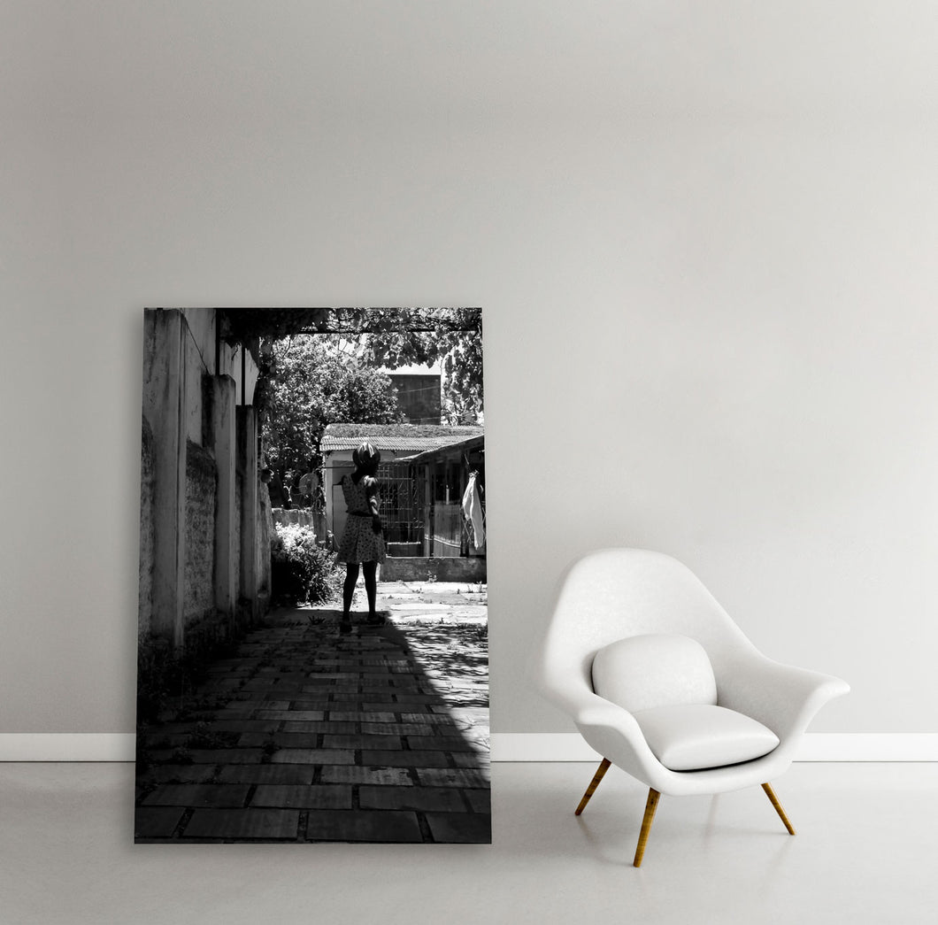 Frame with Black and white image of migrant woman walking in her courtyard in the shadows